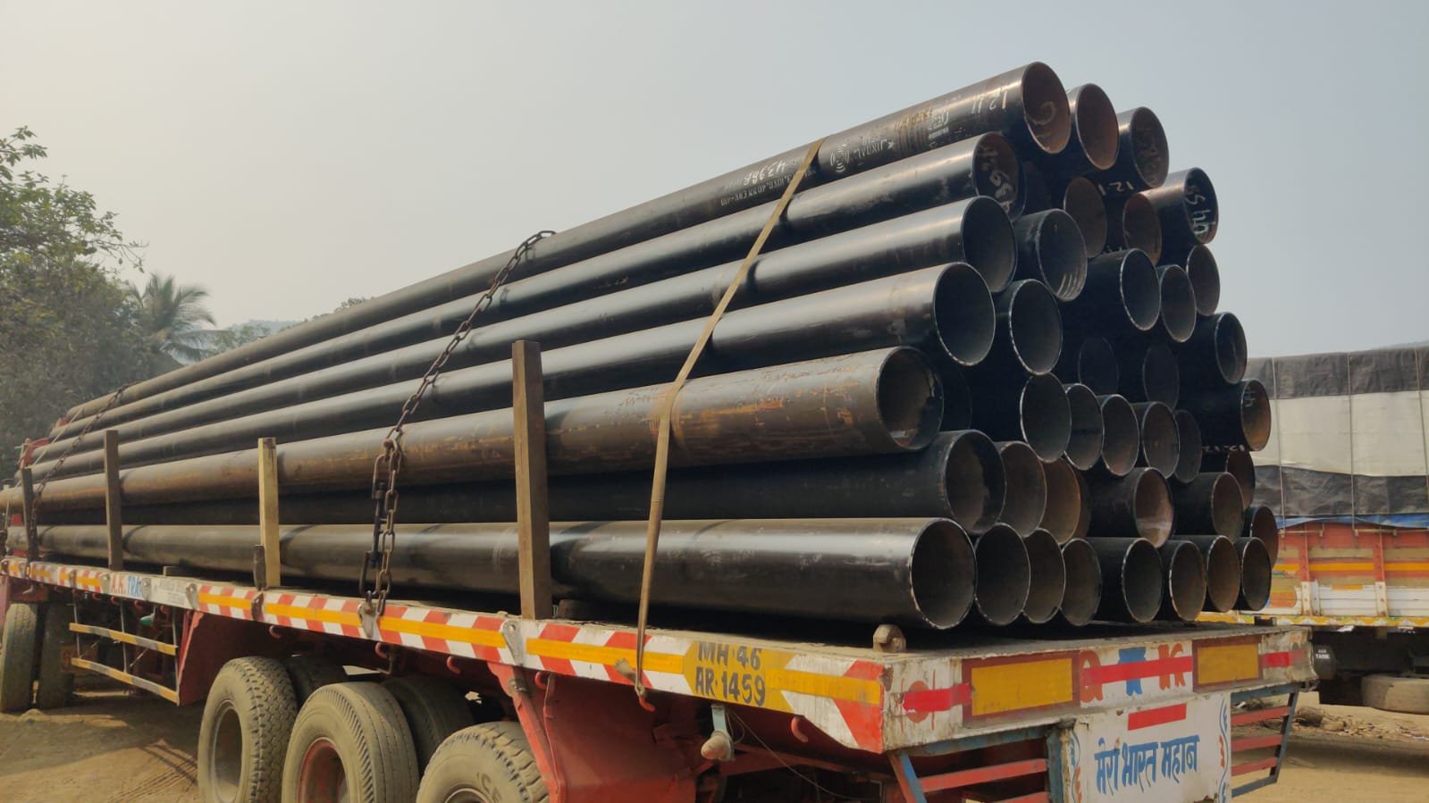 Flatbed transport trailer carrying large-diameter steel line pipes
